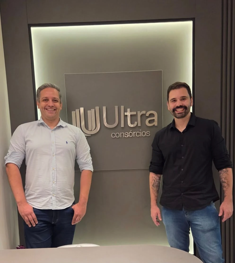 Sócios da Ultra Consórcios em frente ao letreiro da empresa